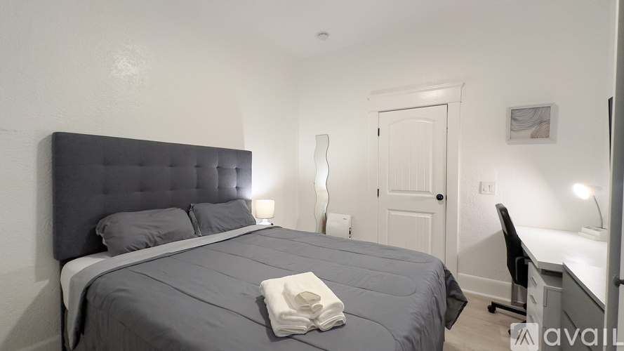A bedroom with a large bed and a desk with a chair.