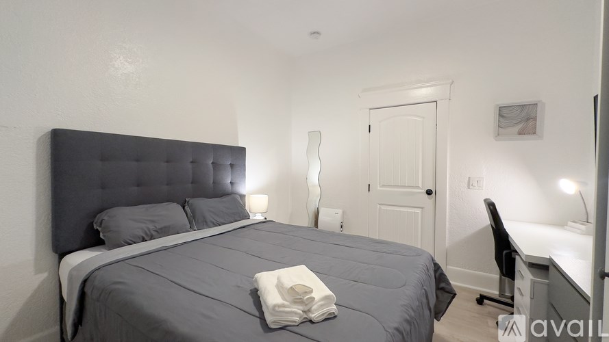 A bedroom with a large bed and a desk with a chair.