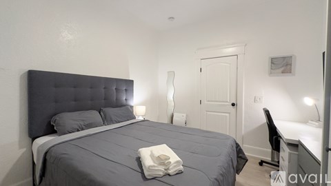 A bedroom with a large bed and a desk with a chair.