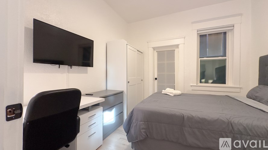 A bedroom with a bed, desk, chair, and a window.