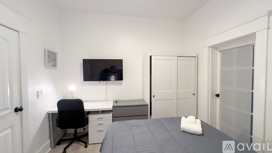 A bedroom with a bed, desk, and chair.