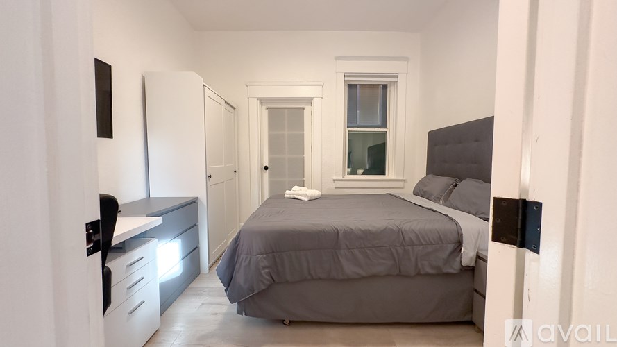 A bedroom with a bed, nightstand, and a window.