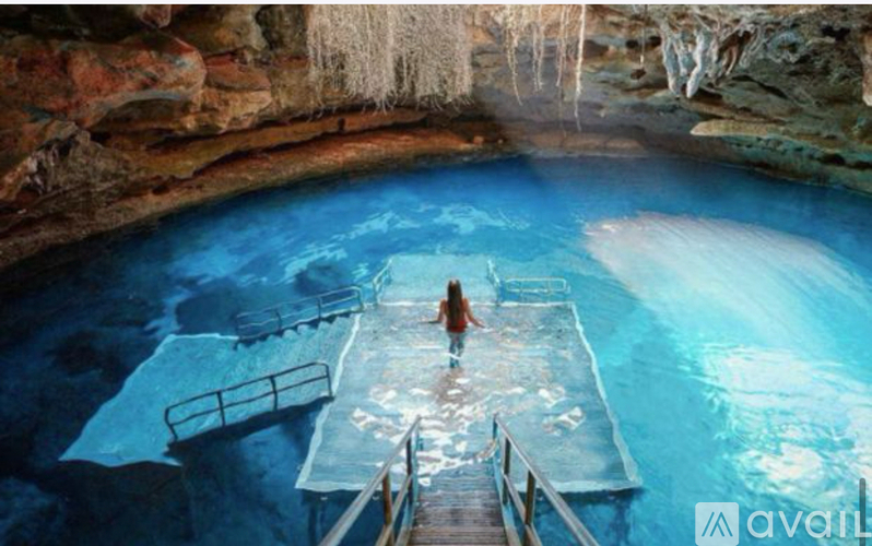 A person is standing in a blue pool with a wooden walkway leading to it.