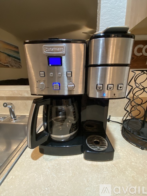 A coffee maker with a digital display and a water filter is on a kitchen counter.