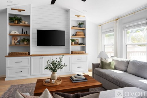 A living room with a grey sofa, a wooden coffee table, and a television on a white cabinet.
