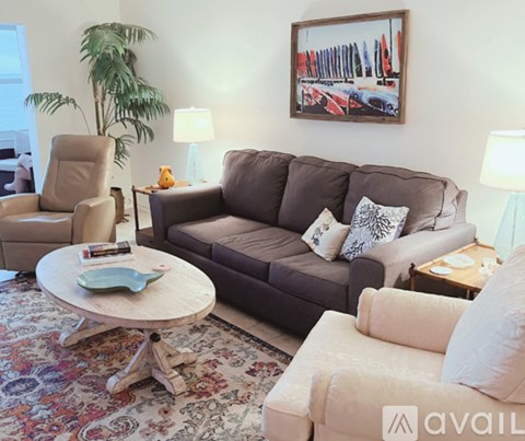 A living room with a brown couch, a chair, a coffee table, and a painting on the wall.