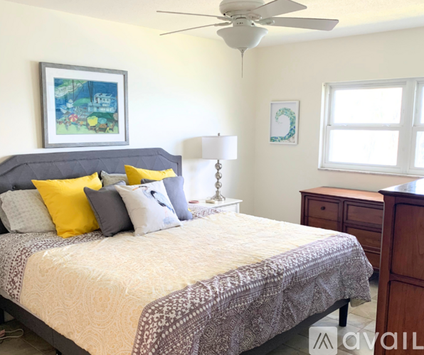 A bedroom with a bed, nightstand, and a painting on the wall.