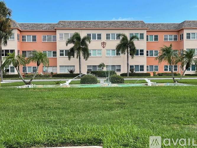 A building with a lawn in front and palm trees around it.