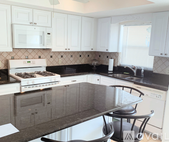 A kitchen with white cabinets and a black countertop.