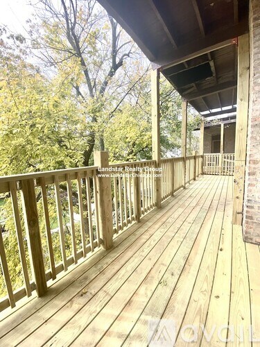 A wooden deck with a railing and trees in the background.