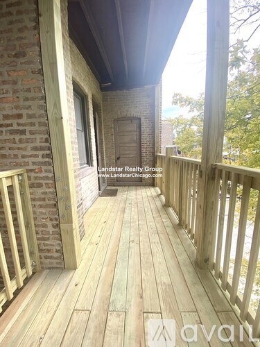 A wooden deck with a brick wall and a door in the background.