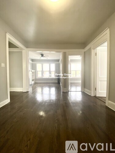 A spacious room with wood flooring and a ceiling fan.