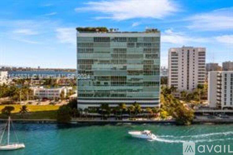 A modern building with a green roof is situated by the water.