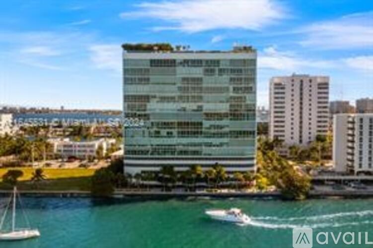 A modern building with a green roof is situated by the water.
