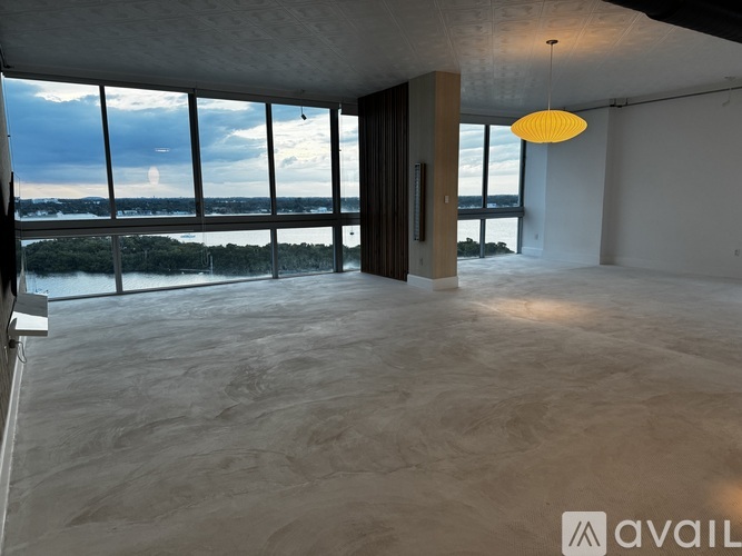 A spacious room with a large window overlooking a body of water.