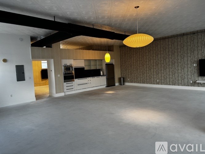 A spacious room with a hanging light fixture and a television on the wall.