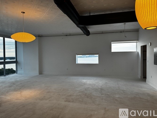 A large empty room with a window and two hanging lamps.