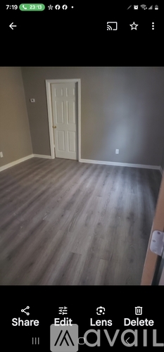 A room with a white door and wooden flooring.