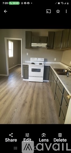 A kitchen with a white stove top oven and wooden flooring.