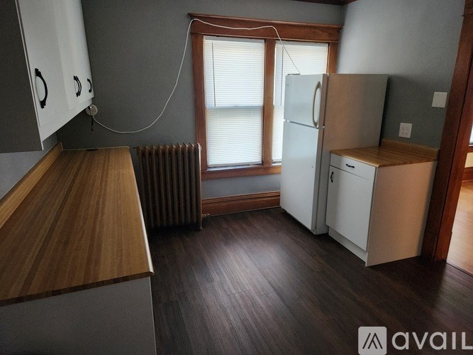 A kitchen with a refrigerator, cabinets, and a window.