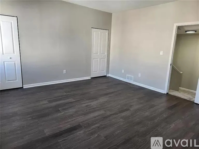 A room with wooden flooring and two doors.