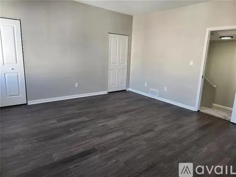 A room with wooden flooring and two doors.