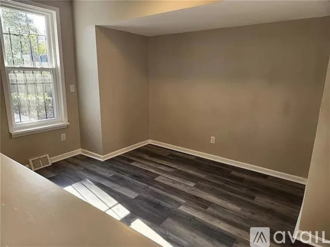 A room with a window and a wooden floor.