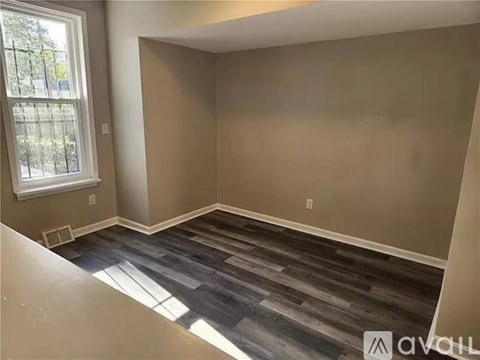 A room with a window and a wooden floor.