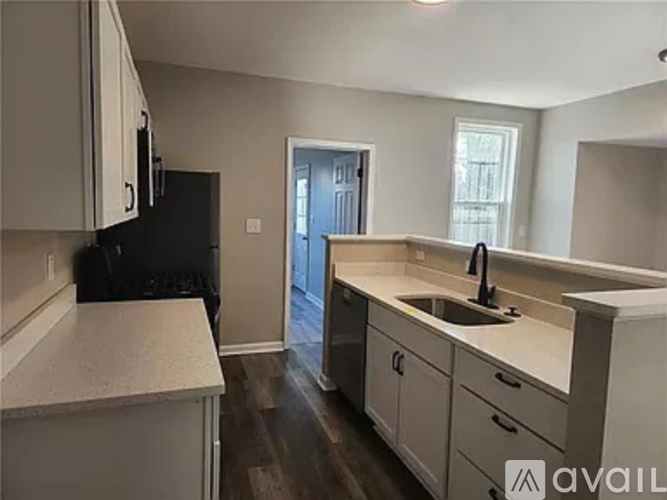 A kitchen with white countertops and a black refrigerator.