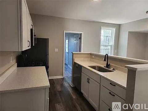 A kitchen with white countertops and a black refrigerator.