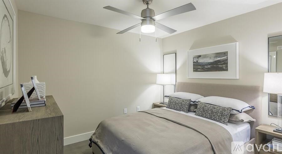 A bedroom with a bed, nightstand, and a ceiling fan.