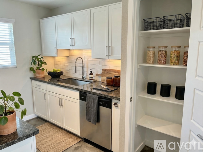 A kitchen with white cabinets and black countertops.