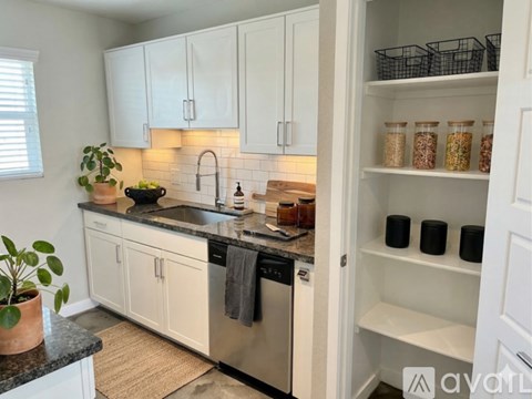 A kitchen with white cabinets and black countertops.