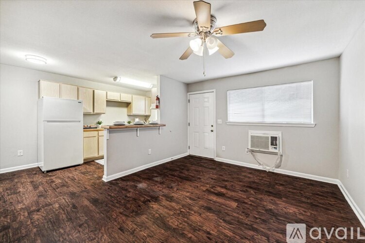 A room with a ceiling fan and a refrigerator.