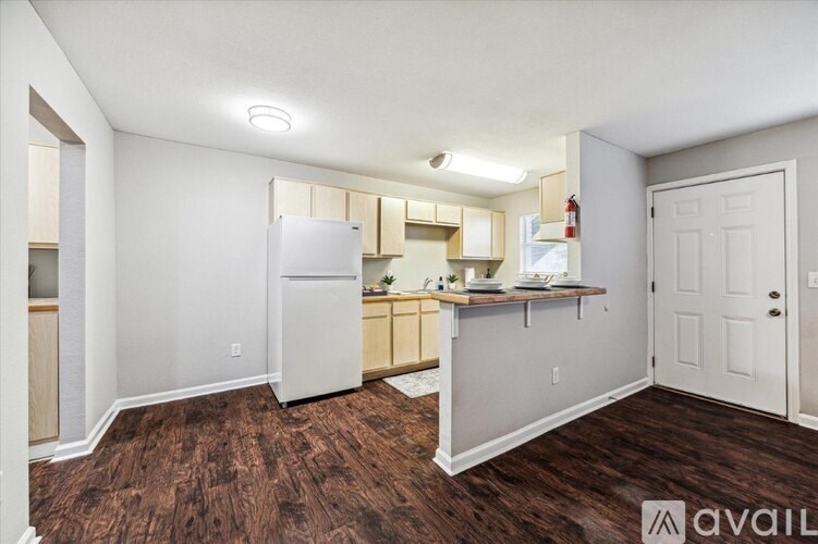 A kitchen area with a refrigerator, cabinets, and a countertop.