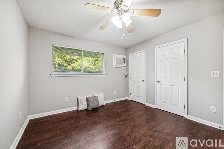 A room with a ceiling fan and a window with a view of trees.