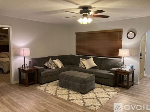 A living room with a grey couch, a rug, and a ceiling fan.