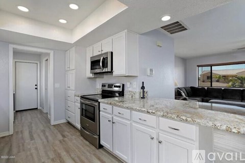 A kitchen with white cabinets and a granite countertop.