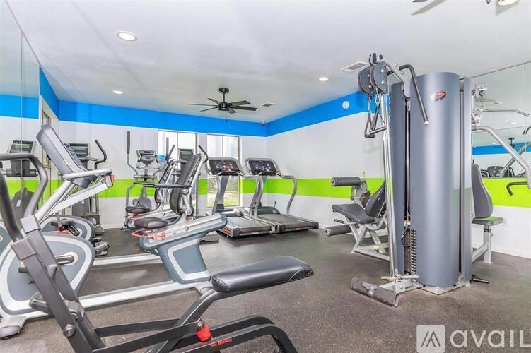 A gym with a variety of equipment including treadmills, weights, and a ceiling fan.
