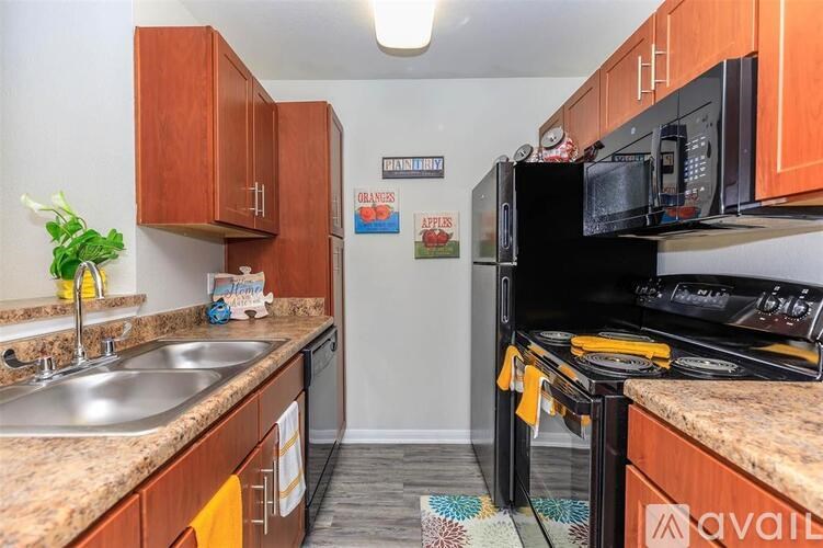 A kitchen with a black fridge and stove, wooden cabinets, and a granite countertop.