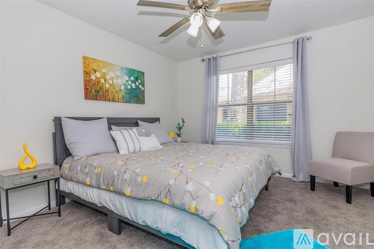 A bedroom with a bed, chair, and a ceiling fan.