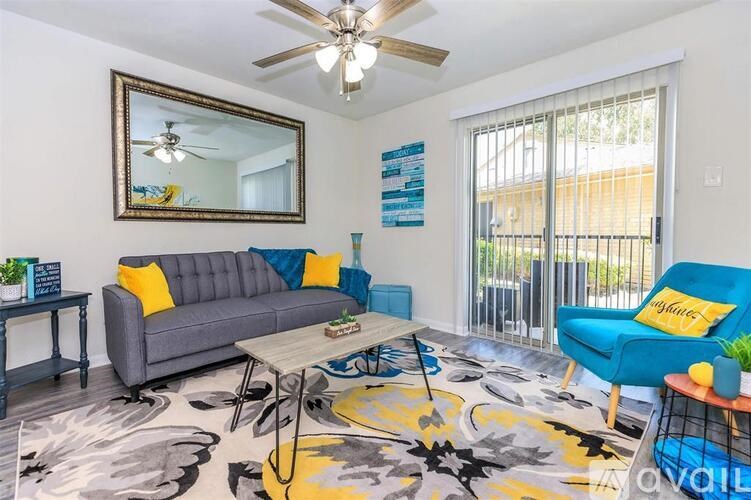 A living room with a grey couch, a blue chair, and a patterned rug.