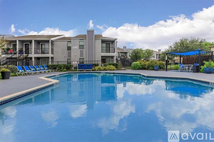 A swimming pool in front of a building with a blue sky and clouds in the background.