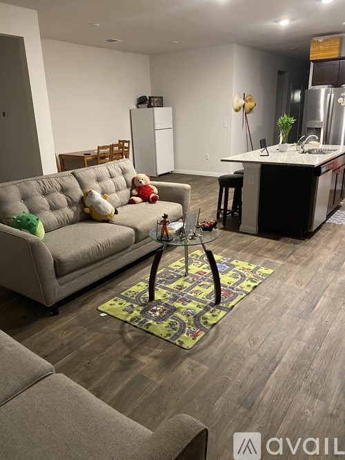 A living room with a grey couch and a rug with a table and chairs in front of it.