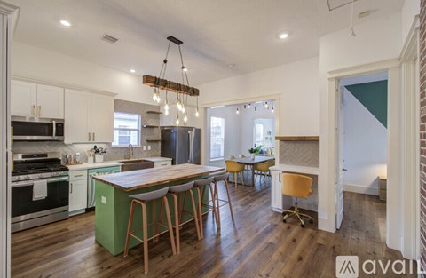 A kitchen with a green island and wooden bar stools.