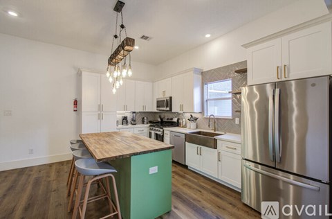 A kitchen with a green island and stainless steel appliances.