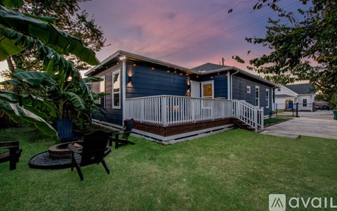A house with a blue exterior and a white fence is shown with a sunset in the background.