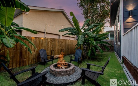 A backyard with a fire pit surrounded by chairs and a wooden fence.
