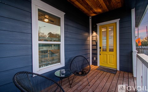 A balcony with a yellow door, a table and a chair.