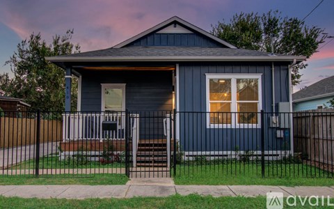A blue house with a black fence and a sign that says "available" in front of it.